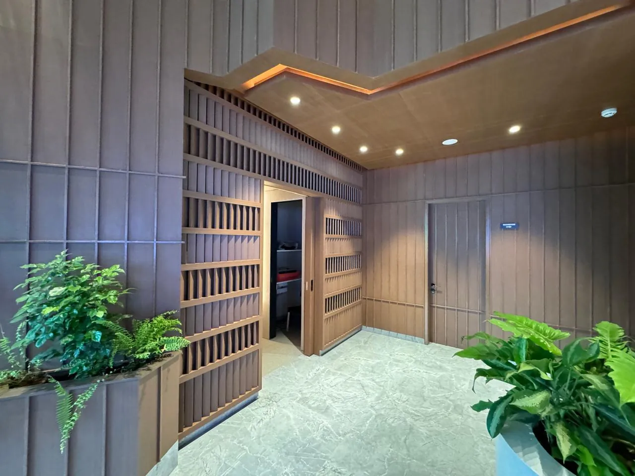 Timber-slatted lounge with greenery and stone floor