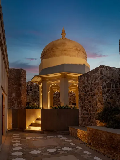 Gilded dome illuminated at dusk beside carved stonework